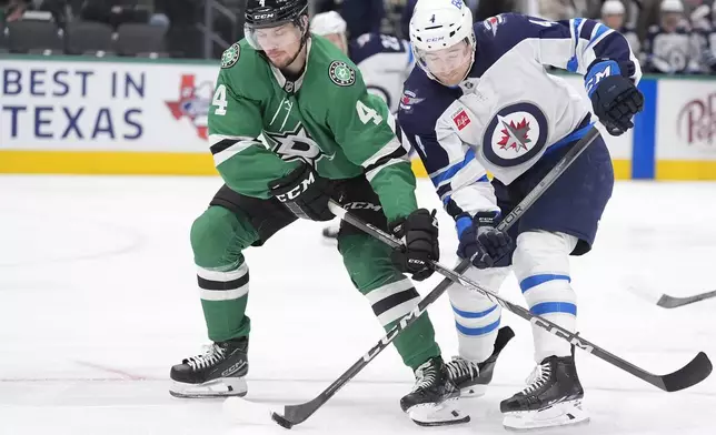 Dallas Stars defenseman Miro Heiskanen, left, and Winnipeg Jets defenseman Neal Pionk, right, try to control the puck during the second period of an NHL hockey game Sunday, Dec. 1, 2024, in Dallas. (AP Photo/LM Otero)