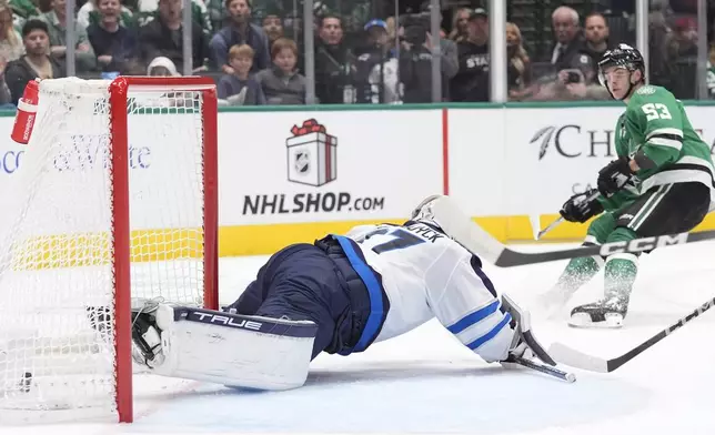 Dallas Stars center Wyatt Johnston (53) scores against Winnipeg Jets goaltender Connor Hellebuyck, left, during the first period of an NHL hockey game Sunday, Dec. 1, 2024, in Dallas. (AP Photo/LM Otero)