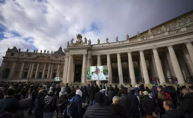 People look at a giant screen in St.Peter's Square, at the Vatican, showing Pope Francis reciting the Angelus noon prayer from his Santa Marta Residence, after he decided not to appear at the window of his studio overlooking the square because of a persistent cold, Sunday, Dec. 22, 2024. (AP Photo/Andrew Medichini)