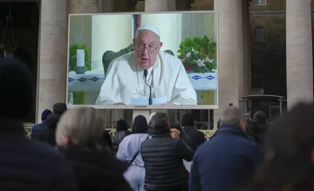 People look at a giant screen in St.Peter's Square, at the Vatican, showing Pope Francis reciting the Angelus noon prayer from his Santa Marta Residence, after he decided not to appear at the window of his studio overlooking the square because of a persistent cold, Sunday, Dec. 22, 2024. (AP Photo/Andrew Medichini)