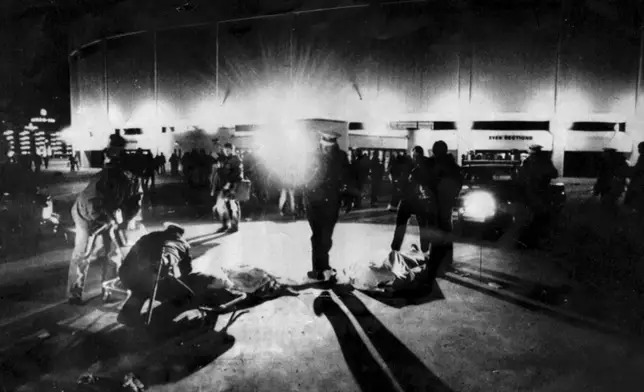 FILE - Cincinnati Police and rescue workers attend to two bodies of people crushed to death outside the fateful The Who concert at Riverfront Coliseum in Cincinnati, Ohio, Dec. 3, 1979. (Ed Reinke/The Cincinnati Enquirer via AP, File)