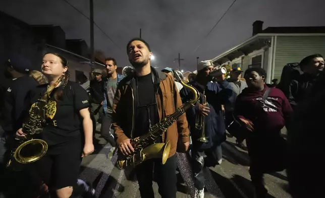 Orlando Prince, a rising jazz musician and son of John "Prince" Gilbert, plays and marches in an emotional second line parade, as a sendoff for his father who recently died, in the Treme section of New Orleans, Monday, Dec. 16, 2024. (AP Photo/Gerald Herbert)