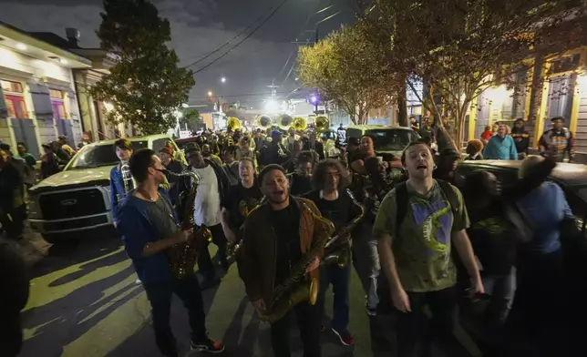 Orlando Prince, center, a rising jazz musician and son of John "Prince" Gilbert, plays and marches in an emotional second line parade, as a sendoff for his father who recently died, in the Treme section of New Orleans, Monday, Dec. 16, 2024. (AP Photo/Gerald Herbert)