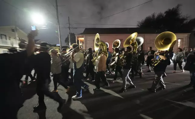 Musicians and friends form a second line parade organized by Orlando Prince, a rising jazz musician, for his father John "Prince" Gilbert, as a sendoff for his father who recently died, in the Treme section of New Orleans, Monday, Dec. 16, 2024. (AP Photo/Gerald Herbert)