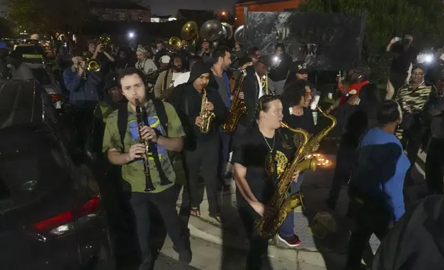 Musicians and friends form a second line parade organized by Orlando Prince, a rising jazz musician, for his father John "Prince" Gilbert, as a sendoff for his father who recently died, in the Treme section of New Orleans, Monday, Dec. 16, 2024. (AP Photo/Gerald Herbert)