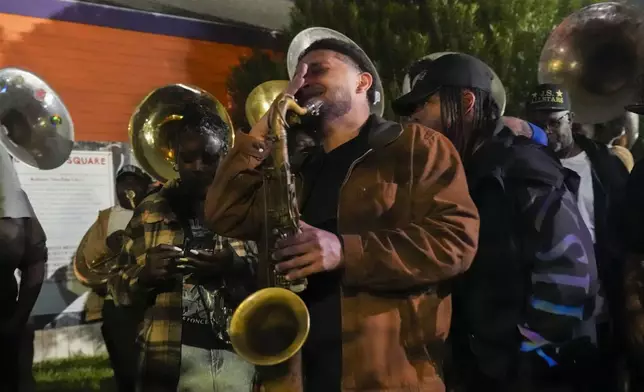 Orlando Prince, a rising jazz musician and son of John "Prince" Gilbert, plays and marches in an emotional second line parade, as a sendoff for his father who recently died, in the Treme section of New Orleans, Monday, Dec. 16, 2024. John "Prince " Gilbert was a founding member of the Rebirth Brass Band and a fixture in the New Orleans Jazz community for decades. (AP Photo/Gerald Herbert)