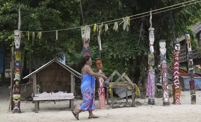 A Moken villager walks in front of spirit poles at Surin Islands in Phang Nga Province, Thailand, Thursday, Dec. 12, 2024. (AP Photo/Sakchai Lalit)