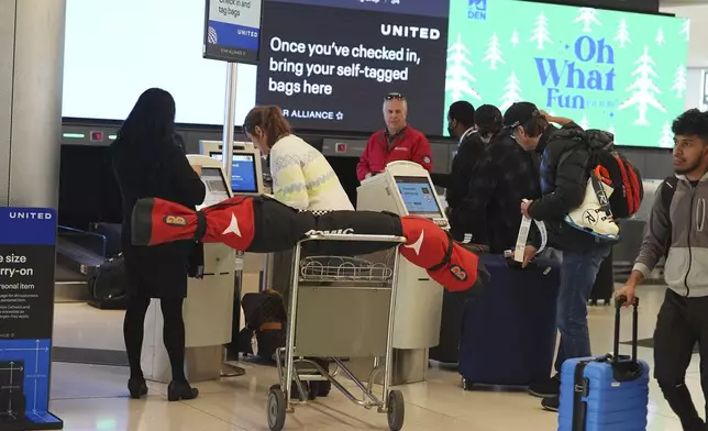 Passengers use the self-check kiosks to get boarding passes for United Airlines flights at Denver International Airport, Saturday, Dec. 14, 2024, in Denver. (AP Photo/David Zalubowski)