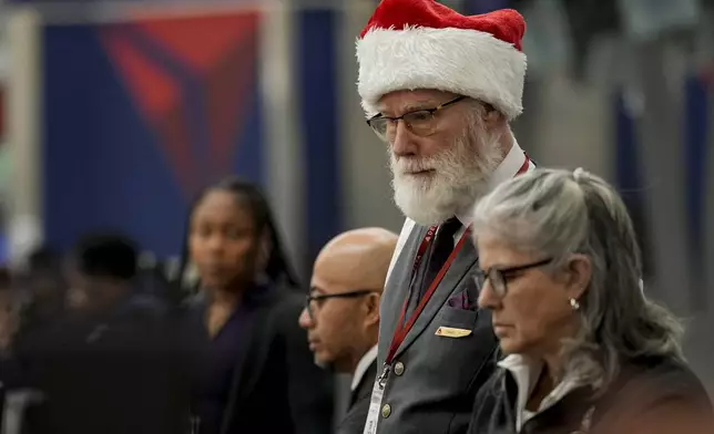 Delta Airlines employee Stanley Davis helps customers as people travel through Hartsfield-Jackson Atlanta International Airport, Friday, Dec. 20, 2024, in Atlanta. (AP Photo/Mike Stewart)