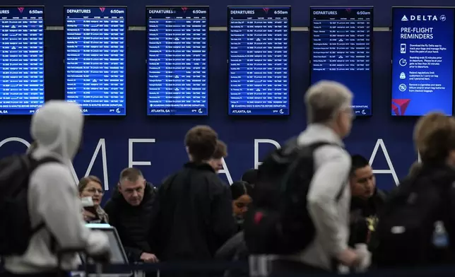 Travelers move through Hartsfield-Jackson Atlanta International Airport, Friday, Dec. 20, 2024, in Atlanta. (AP Photo/Mike Stewart)