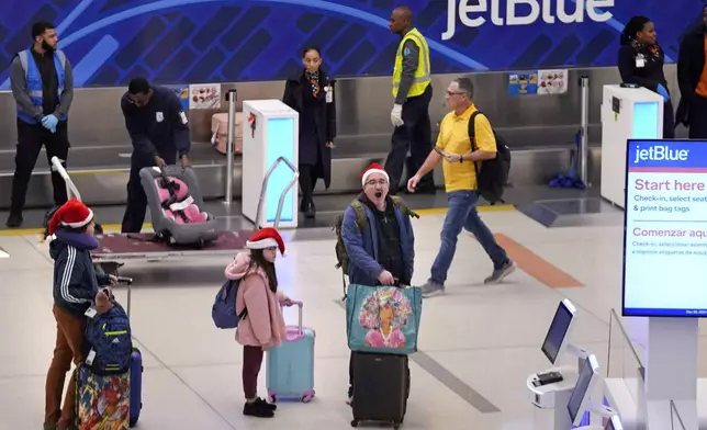 Holiday traveler Julio Henriquez of Canton, Mass., yawns while traveling with his children Marcelo and Amanda at Logan Airport, Friday, Dec. 20, 2024, in Boston. (AP Photo/Charles Krupa)