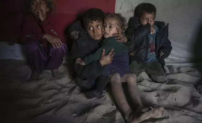 Palestinian Tamim Marouf, 6, sits inside his family's tent alongside his sister Hala, 10, and his brother Malek, 4, at a camp for internally displaced Palestinians on the beachfront in Deir al-Balah, central Gaza Strip, Friday, Dec. 27, 2024. (AP Photo/Abdel Kareem Hana)
