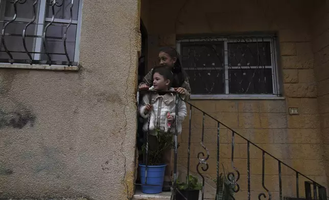 Palestinian girls watch the funeral of Zein Atatrah, 18, as they stand on the steps of their house, in the West Bank town of Ya'bad Friday, Dec. 27, 2024. (AP Photo/Nasser Nasser)