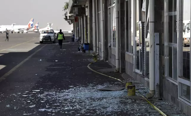 Workers walk past broken glass in Sana'a International Airport following Thursday's Israeli airstrikes on Yemen, Friday, Dec. 27, 2024. The Israeli military reported targeting infrastructure used by the Houthis at the Sanaa International Airport, as well as ports in Hodeida, Al-Salif, and Ras Qantib, along with power stations Thursday Dec. 26..(AP Photo/Osamah Abdulrahman)