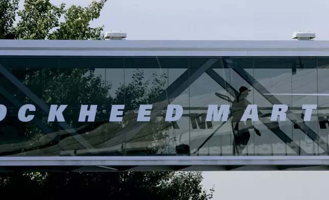 FILE - A man walks past a Lockheed Martin logo as he walks through a section of the company's chalet bridging a road at Farnborough International Airshow in Farnborough, southern England, July 19, 2006. (AP Photo/Matt Dunham, File)