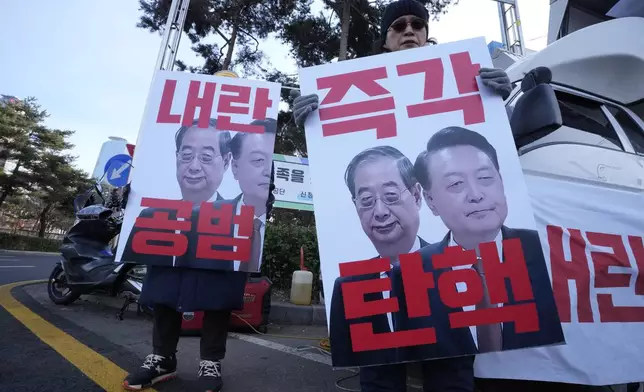 Protesters hold banners showing images of impeached President Yoon Suk Yeol, right, and acting President Han Duck-soo during a rally demanding Han's impeachment outside of the National Assembly in Seoul, South Korea, Dec. 27, 2024. The signs read "Impeachment immediately" (AP Photo/Ahn Young-joon)