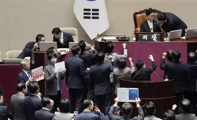 Lawmakers, left, of South Korea's opposition Democratic Party, hold signs as lawmakers of the ruling People Power Party protesting to South Korea's National Assembly Speaker Woo Won Shik, top second from right, during a plenary session for the impeachment motion against South Korean acting President Han Duck-soo at the National Assembly in Seoul, South Korea, Dec. 27, 2024. The signs read "People Power Party is an accomplice of rebellion". (AP Photo/Ahn Young-joon)