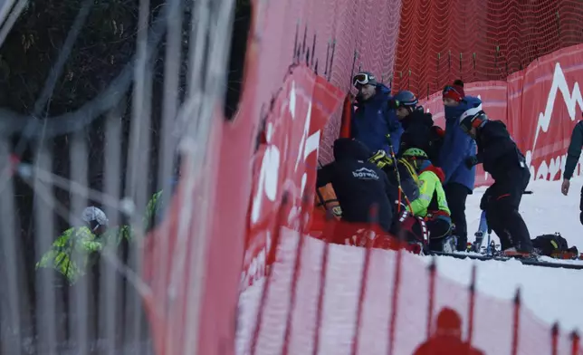 Medical staff are helping France's Cyprien Sarrazin after crashing into protections net during an alpine ski, men's World Cup downhill training, in Bormio, Italy, Friday, Dec. 27, 2024. (AP Photo/Alessandro Trovati)