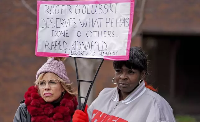 Lesa Mensa, left, and Anita Randle listen to a speaker at a rally outside the federal courthouse on was was to be the opening day for a trial for former police detective Roger Golubski, Monday, Dec. 2, 2024, in Topeka, Kan. (AP Photo/Charlie Riedel)