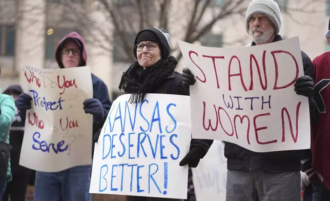 People listen to a speaker at a rally outside the federal courthouse on was was to be the opening day for a trial for former police detective Roger Golubski, Monday, Dec. 2, 2024, in Topeka, Kan. (AP Photo/Charlie Riedel)