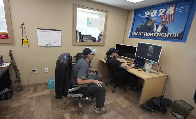 Anton Kytaiev, right, works on a social media post for Ron Hubbard, owner of Atlas Survival Shelters, at the company's office in Sulphur Springs, Texas, Tuesday, Aug. 27, 2024, (AP Photo/LM Otero)