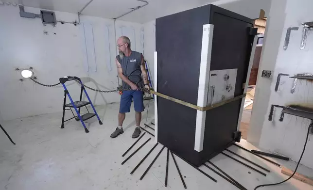 Chris Pettis helps installs a safe in a bunker under construction for a client at Atlas Survival Shelters in Sulphur Springs, Texas, on Aug. 27, 2024, (AP Photo/LM Otero)