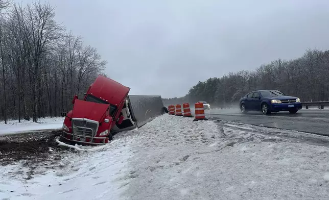 A tractor-trailer hauling a load of oranges sits on the side of the road after sliding off the Maine Turnpike early on Wednesday, Dec. 11, 2024, in New Gloucester, Maine. (AP Photo/David Sharp)