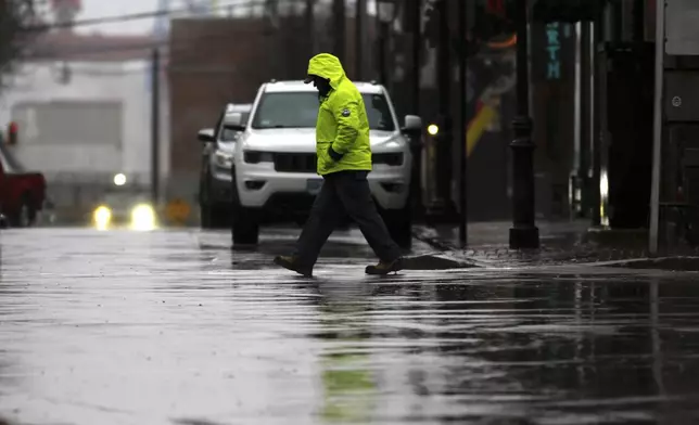 A person walks through the rain as a storm system and possible "bomb cyclone" hit the U.S. East Coast, Wednesday, Dec. 11, 2024 in Portsmouth, N.H. (AP Photo/Caleb Jones)