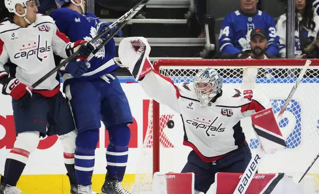 Toronto Maple Leafs' John Tavares, second from left, scores against Washington Capitals goaltender Logan Thompson, right, during first-period NHL hockey game action in Toronto, Saturday, Dec. 28, 2024. (Frank Gunn/The Canadian Press via AP)