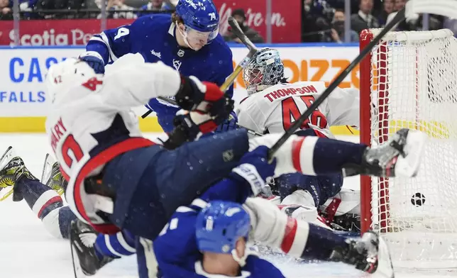 Toronto Maple Leafs' Bobby McMann (74) scores against Washington Capitals goaltender Logan Thompson (48) as Capitals' Martin Fehervary (42) and Maple Leafs' Max Domi (11) collide during second-period NHL hockey game action in Toronto, Saturday, Dec. 28, 2024. (Frank Gunn/The Canadian Press via AP)