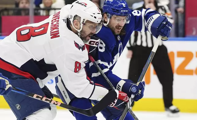 Washington Capitals' Alex Ovechkin, left, battles with Toronto Maple Leafs' Chris Tanev, right, during first-period NHL hockey game action in Toronto, Saturday, Dec. 28, 2024. (Frank Gunn/The Canadian Press via AP)