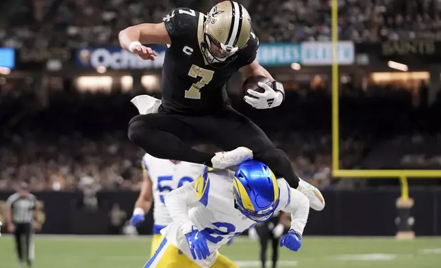 New Orleans Saints tight end Taysom Hill (7) leaps over Los Angeles Rams cornerback Darious Williams (24) during the first half of an NFL football game Sunday, Dec. 1, 2024, in New Orleans. (AP Photo/Gerald Herbert)