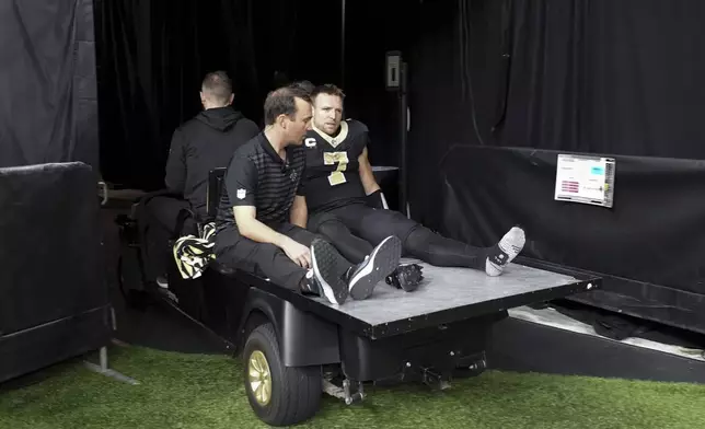 New Orleans Saints tight end Taysom Hill (7) is carted off the field during the second half of an NFL football game against the Los Angeles Rams, Sunday, Dec. 1, 2024, in New Orleans. (AP Photo/Gerald Herbert)