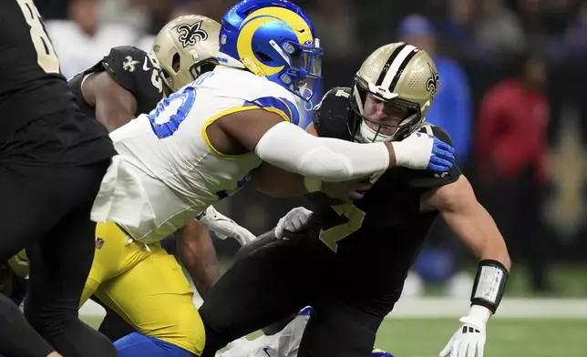 New Orleans Saints tight end Taysom Hill (7) is tackled by Los Angeles Rams defensive tackle Tyler Davis (90) during the first half of an NFL football game Sunday, Dec. 1, 2024, in New Orleans. (AP Photo/Gerald Herbert)