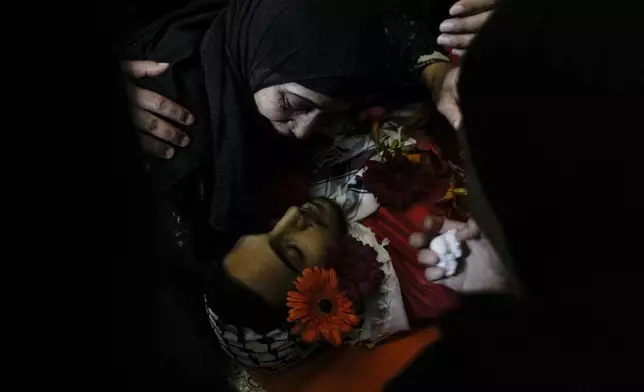 The mother of Ahmed Nidal Aslan, who was killed during clashes with Israeli forces, mourns over his body during his funeral in the West Bank refugee camp of Qalandiya, on July 24, 2024. (AP Photo/Mahmoud Illean)