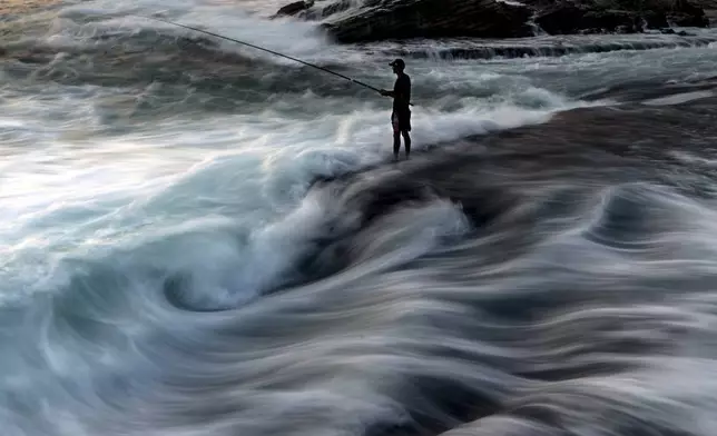 A fisherman casts his fishing line into the Mediterranean Sea from a rocky area along the coastline in Beirut, Lebanon, on July 27, 2024. (AP Photo/Hassan Ammar)