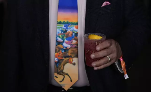 A race fan holds a drink as he walks on the grounds of Churchill Downs in Louisville, Ky., before the 150th running of the Kentucky Oaks horse race on May 3, 2024. (AP Photo/Charlie Riedel)