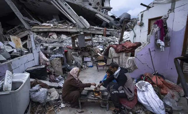 Members of the Al-Rabaya family break their fast during the Muslim holy month of Ramadan outside their home, which was destroyed by an Israeli airstrike, in Rafah, Gaza Strip, on March 18, 2024. (AP Photo/Fatima Shbair)