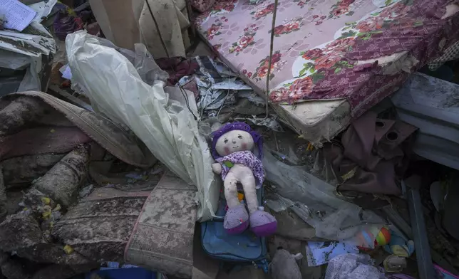 A doll lies among plastic debris and clothes in the aftermath of an Israeli airstrike at the Muwassi camp near Khan Younis, in the southern Gaza Strip, on Thursday, Dec. 5, 2024. Israeli airstrikes struck the camp for displaced Palestinians in southern Gaza on Wednesday, killing at least 21 people, according to the head of a nearby hospital. (AP Photo/Abdel Kareem Hana)