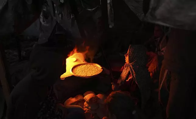 A displaced Palestinian woman bakes biscuits and breads on a makeshift oven as she sits on a tent set up on an area in Deir al-Balah, Gaza Strip Thursday, Dec. 5, 2024. (AP Photo/Abdel Kareem Hana)