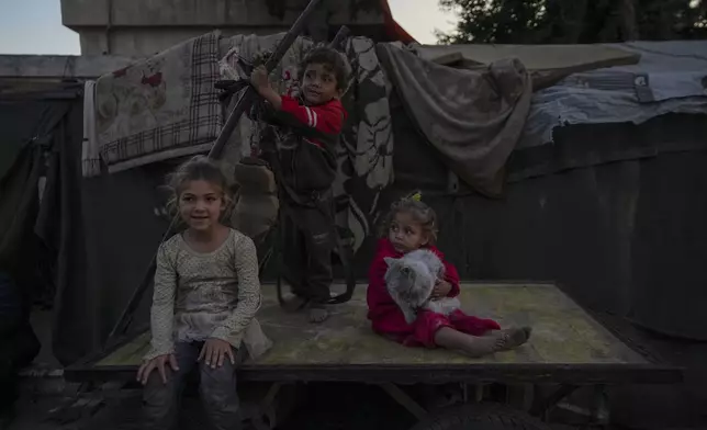 Displaced Palestinians children play next to tents set up on an area in Deir al-Balah, Gaza Strip Thursday, Dec. 5, 2024. (AP Photo/Abdel Kareem Hana)