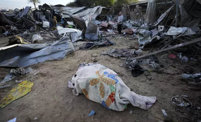 A body recovered earlier lies on the ground at the Muwassi camp near Khan Younis, in the southern Gaza Strip, on Thursday, Dec. 5, 2024. Israeli airstrikes hit the camp for displaced Palestinians in southern Gaza on Wednesday, killing at least 21 people, according to the head of a nearby hospital. (AP Photo/Abdel Kareem Hana)