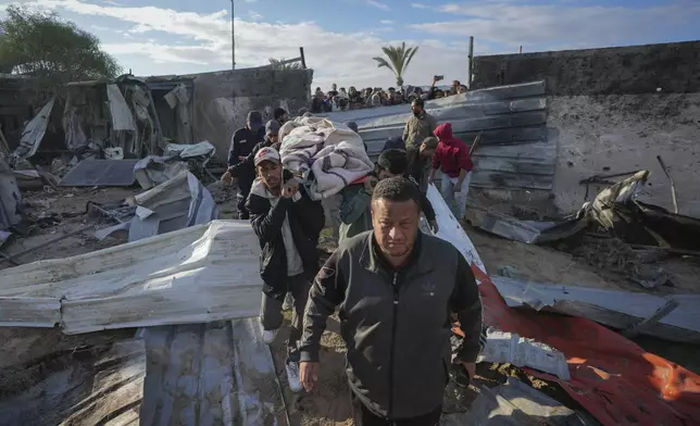 A body is recovered from the debris in the aftermath of an Israeli airstrike at the Muwassi camp near Khan Younis, in the southern Gaza Strip, on Thursday, Dec. 5, 2024. Israeli airstrikes struck the camp for displaced Palestinians in southern Gaza on Wednesday, killing at least 21 people, according to the head of a nearby hospital. (AP Photo/Abdel Kareem Hana)