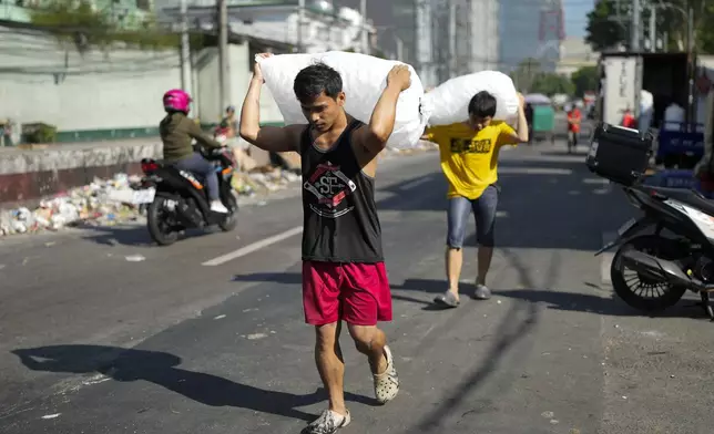 FILE - Men deliver sacks of ice cubes as demand remains high due to hot temperatures in Quezon city, Philippines on April 24, 2024. (AP Photo/Aaron Favila, File)