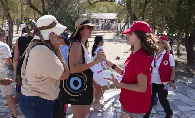 FILE - A Red Cross volunteer gives water to tourists at the foot of the Acropolis hill during a hot and windy day in Athens, July 17, 2024. (AP Photo/Petros Giannakouris, File)