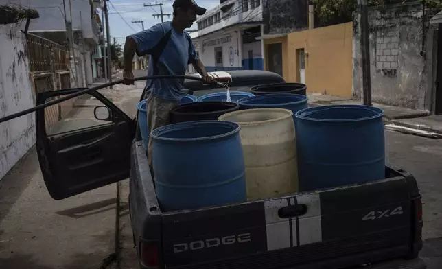 FILE - A man fills containers with water due to the shortage caused by high temperatures and drought in Veracruz, Mexico, on June 16, 2024. (AP Photo/Felix Marquez, File)