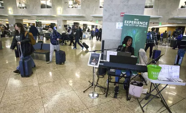 Roz McCommon performs amid travelers at Seattle-Tacoma International Airport on November 26, 2024, in SeaTac, Wash. (AP Photo/Manuel Valdes)