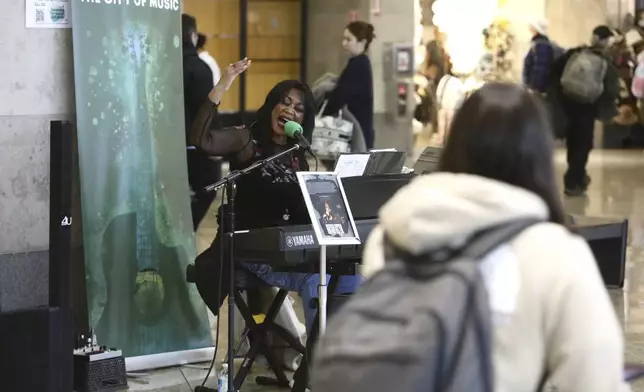 CORRECTS SPELLING OF SINGERS LAST NAME TO MCCOMMON - Roz McCommon performs amid travelers at Seattle-Tacoma International Airport on November 26, 2024, in SeaTac, Wash. (AP Photo/Manuel Valdes)