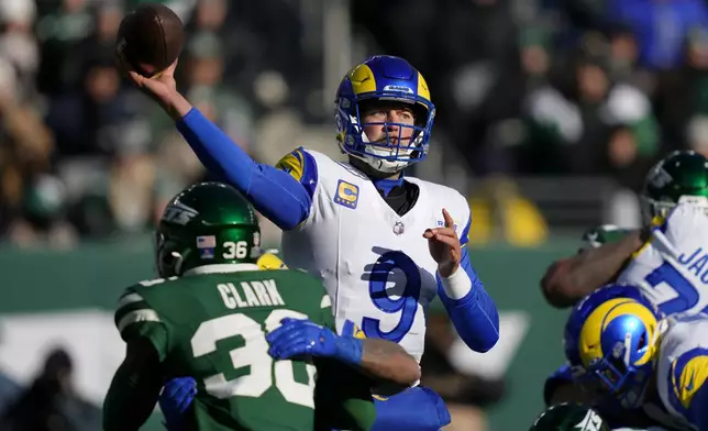 Los Angeles Rams quarterback Matthew Stafford (9) passes as New York Jets safety Chuck Clark, bottom left, applies pressure during the first half of an NFL football game in East Rutherford, N.J., Sunday, Dec. 22, 2024. (AP Photo/Julia Demaree Nikhinson)