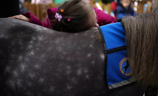 A student at a school for disabled children hugs Ivi, a miniature horse used for therapy programs, in Athens, Greece, on Thursday, Nov. 21, 2024. (AP Photo/Thanassis Stavrakis)